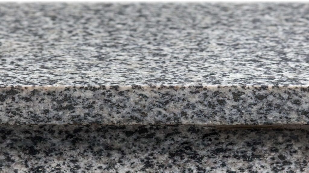 Close-up of a polished granite surface with a speckled pattern in shades of black, white, and gray, perfect for any countertop installation or kitchen remodeling project.